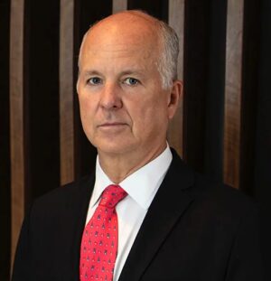 A man in suit and tie standing next to a wooden wall.